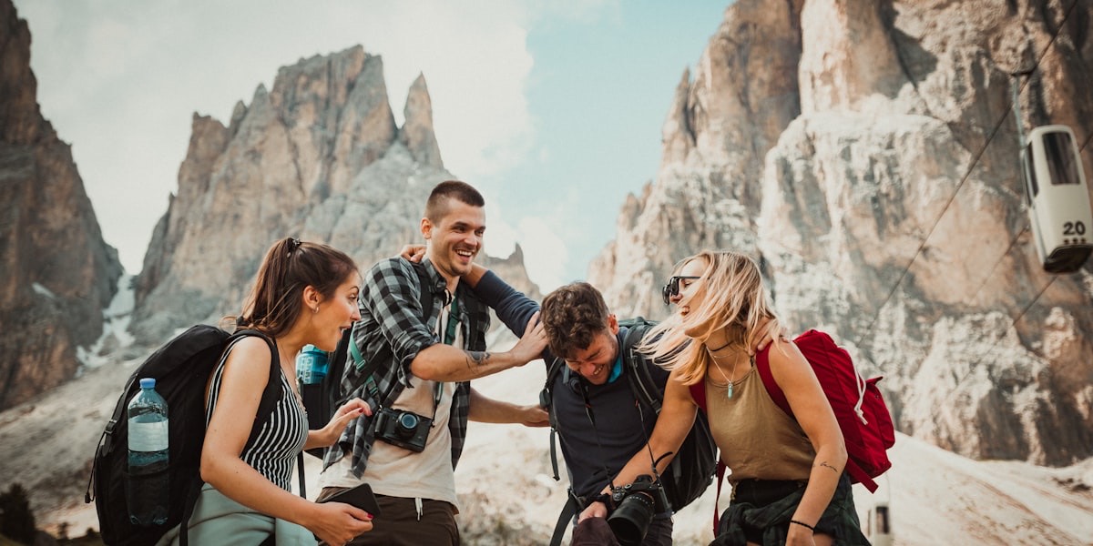 Groupe de quatre randonneurs riant ensemble devant les sommets rocheux des Dolomites