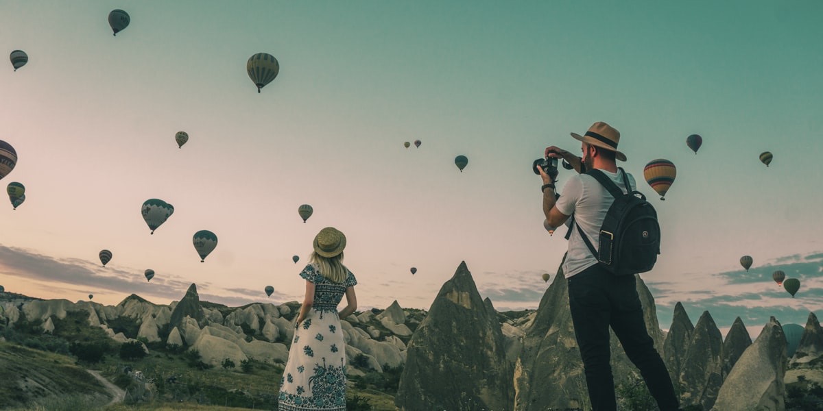 Photographe observant un lever de soleil sur des montgolfières au-dessus des cheminées de fées de Cappadoce