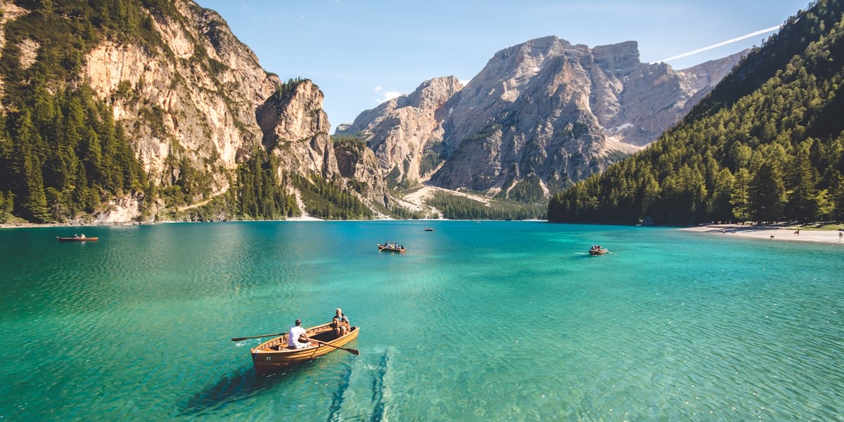 Barques en bois sur les eaux transparentes d'un lac alpin, au pied de falaises boisées