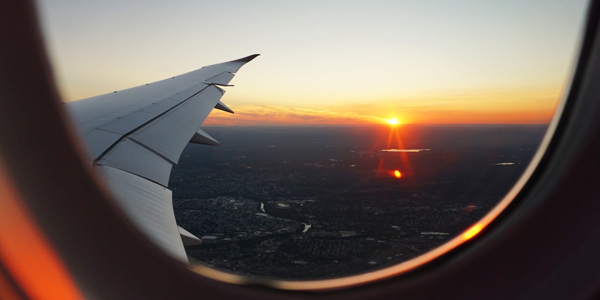Vue depuis un hublot d'avion sur l'aile et un coucher de soleil au-dessus d'une ville